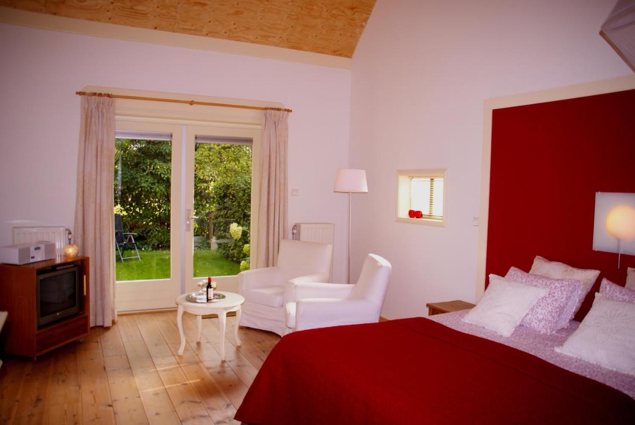 a bedroom with a red bed and a living room at De Heerlijkheid Ruinerwold in Ruinerwold