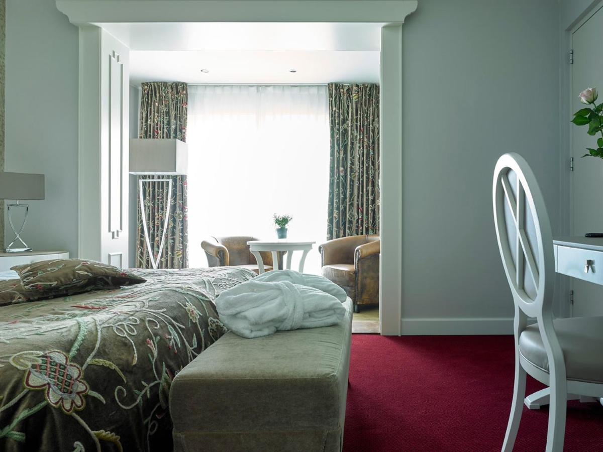 a bedroom with a bed and a table and a window at Romantik Parkhotel het Gulpdal in Slenaken