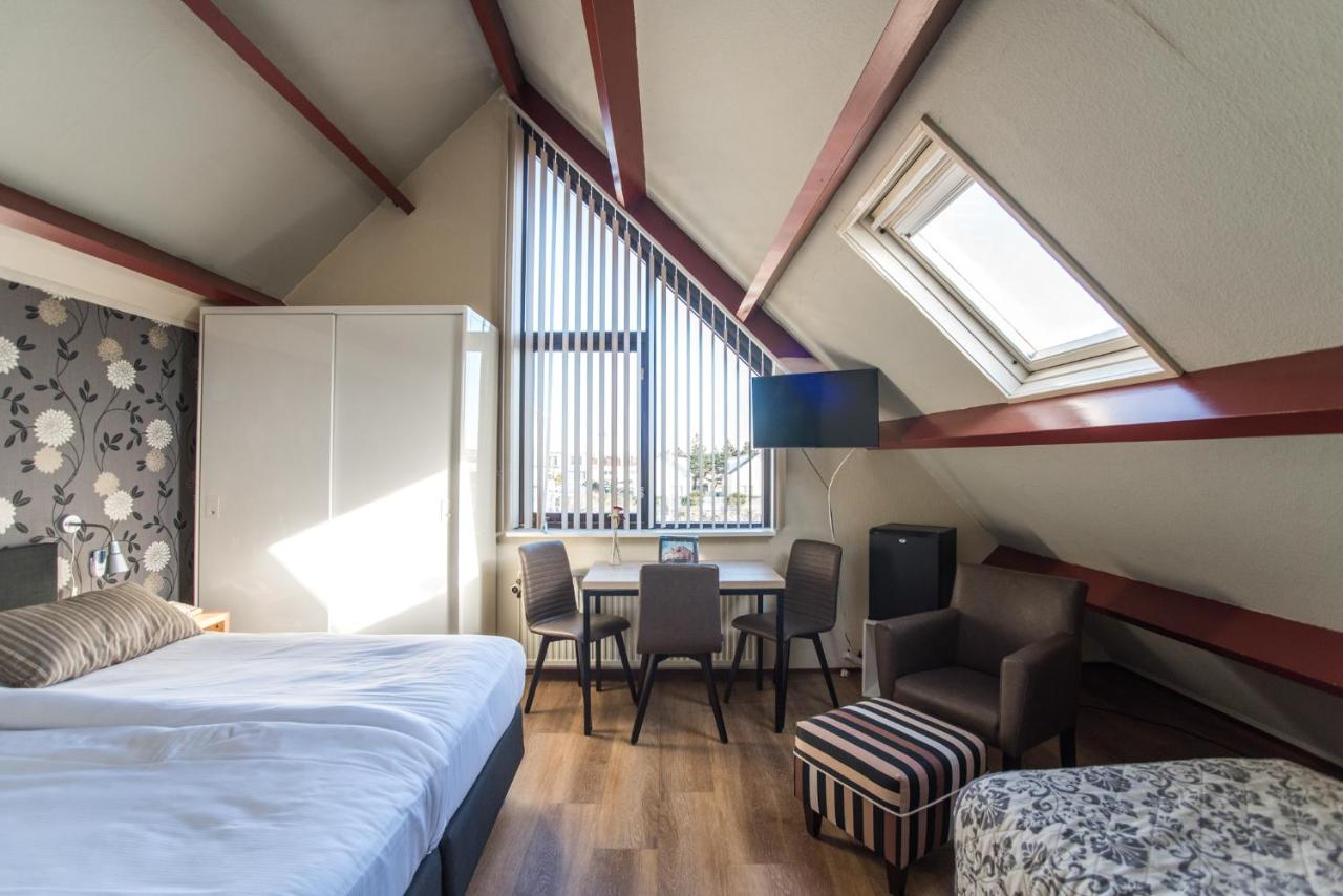 a bedroom with a bed and a table and chairs at Hotel Faber in Zandvoort
