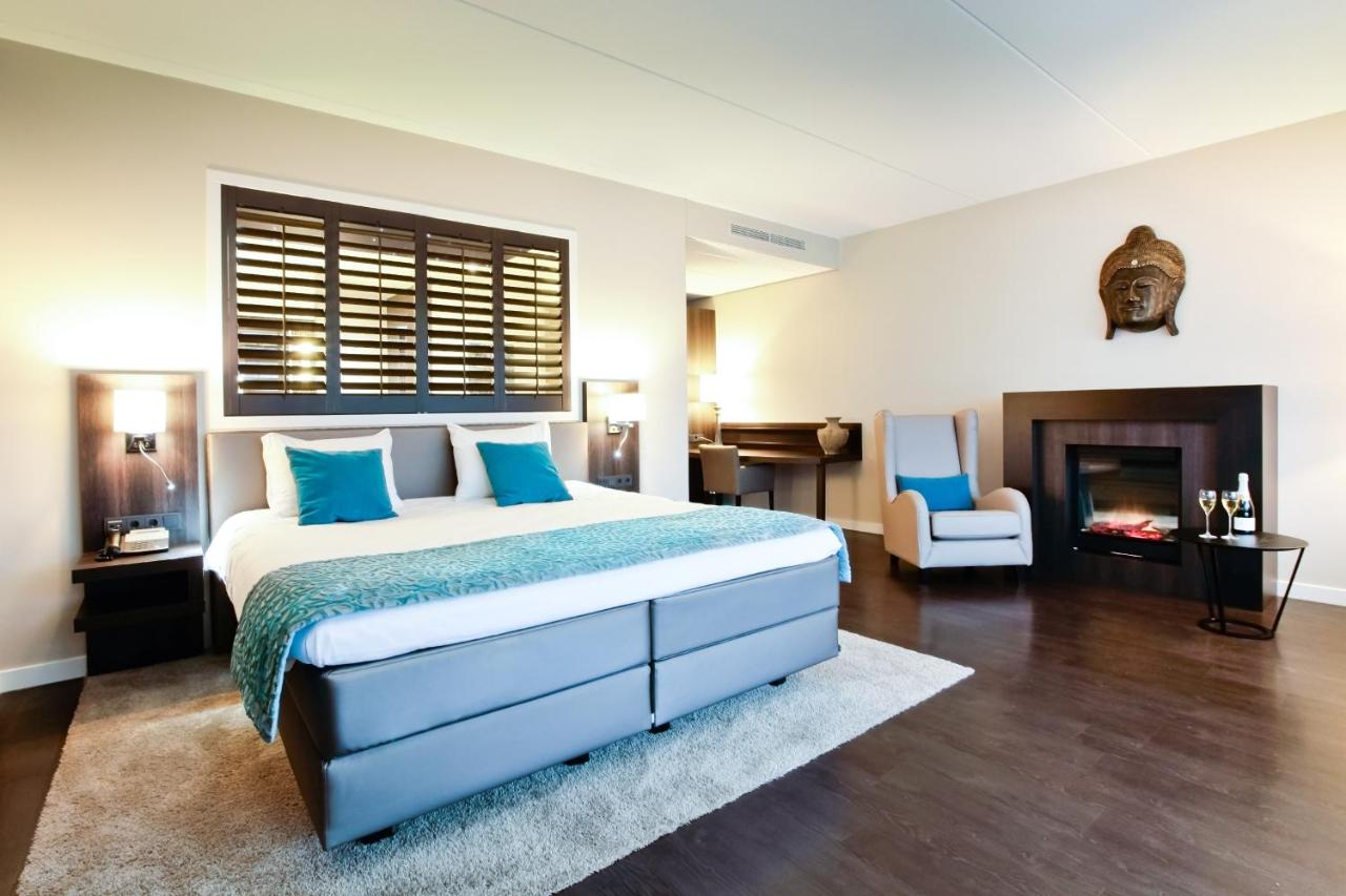 a bedroom with a large bed and a fireplace at Hotel Thermen Bussloo - Apeldoorn in Bussloo
