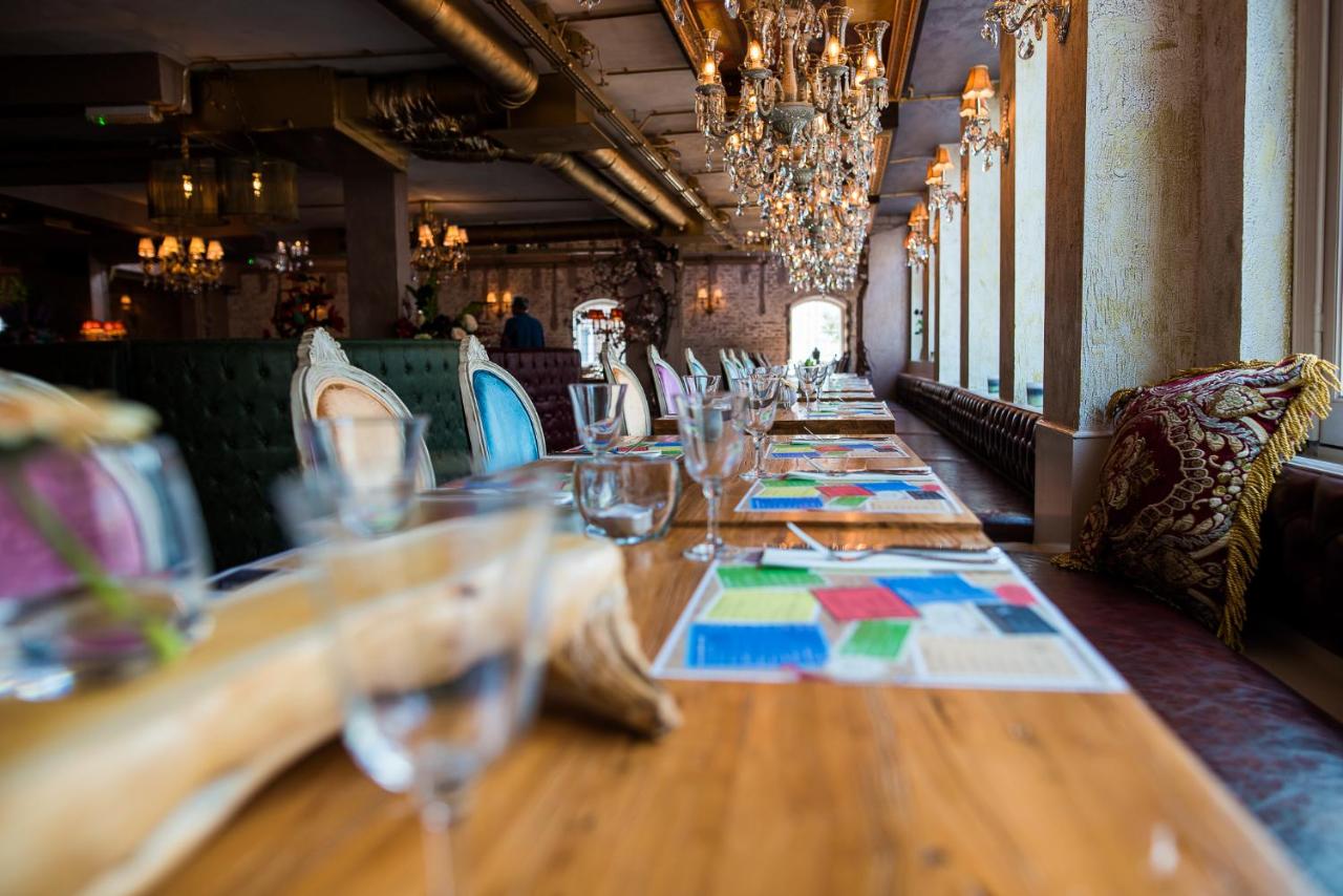 a long wooden table in a restaurant with wine glasses at Hotel The Stamp in Den Bosch
