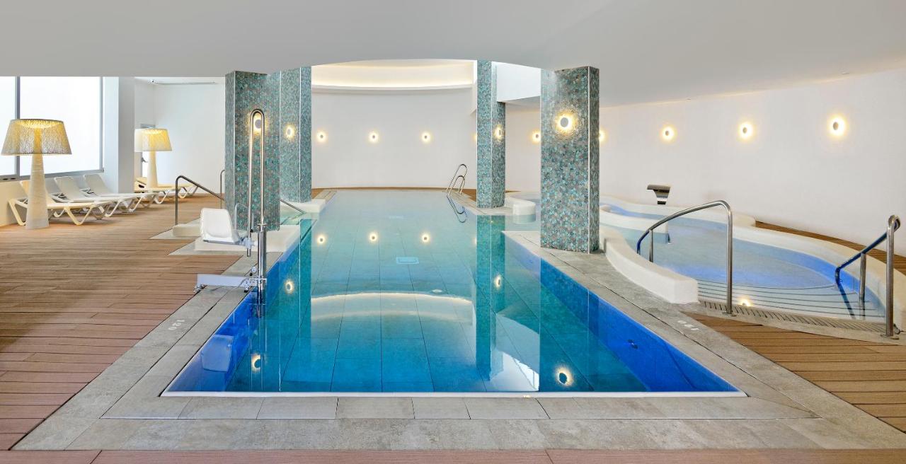 Indoor swimming pool with surrounding lounge chairs and ambient lighting.