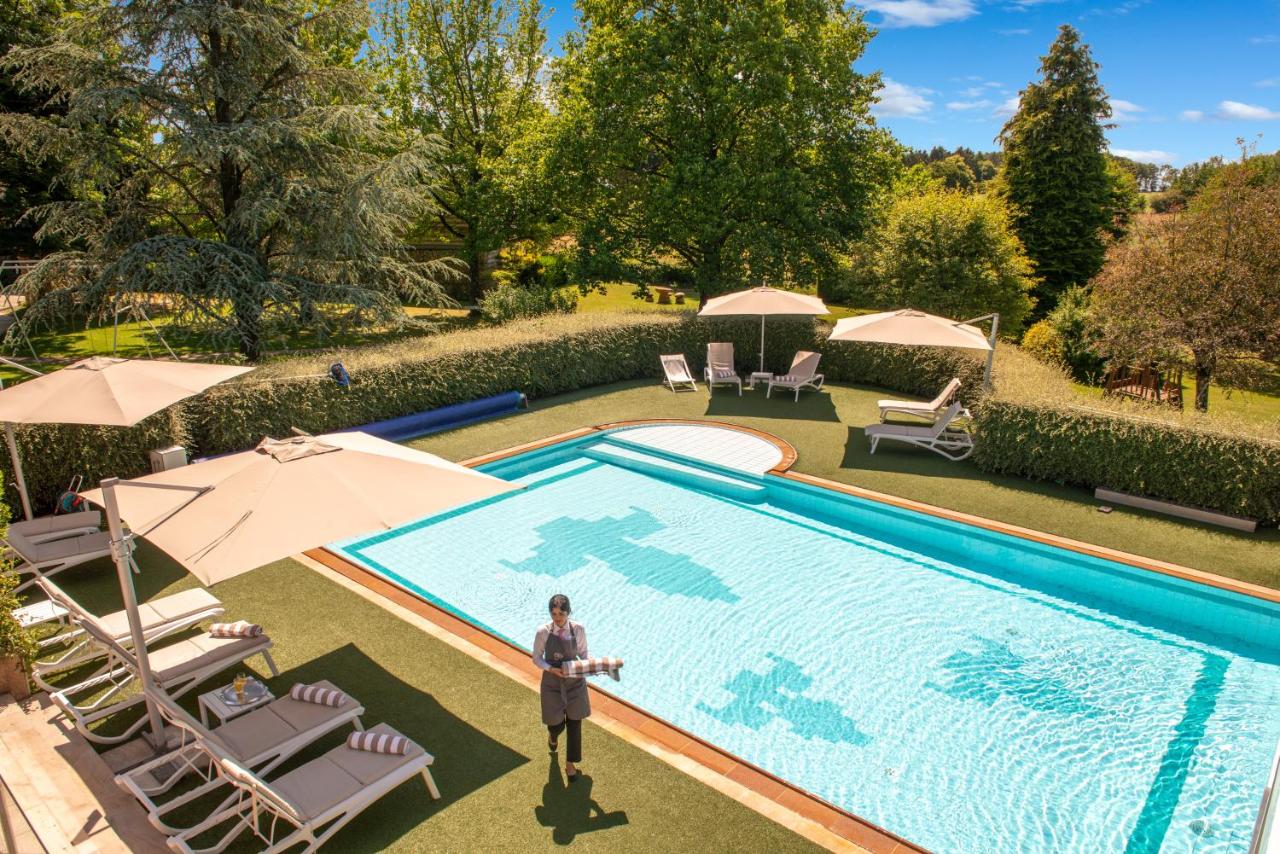 a man standing in front of a swimming pool at Le Manoir du Lys, The Originals Relais in Bagnoles de l'Orne