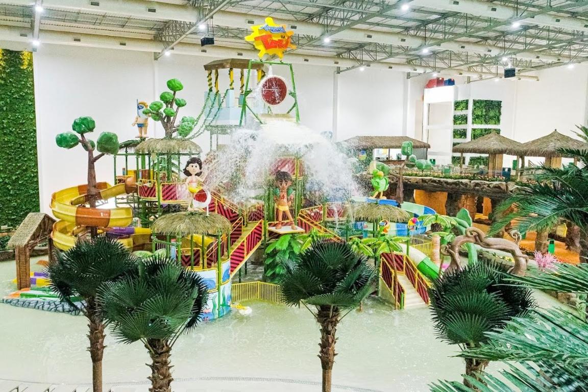 Grande parque aquático infantil indoor com 3 escorregadores em curva coloridos e baldão de água