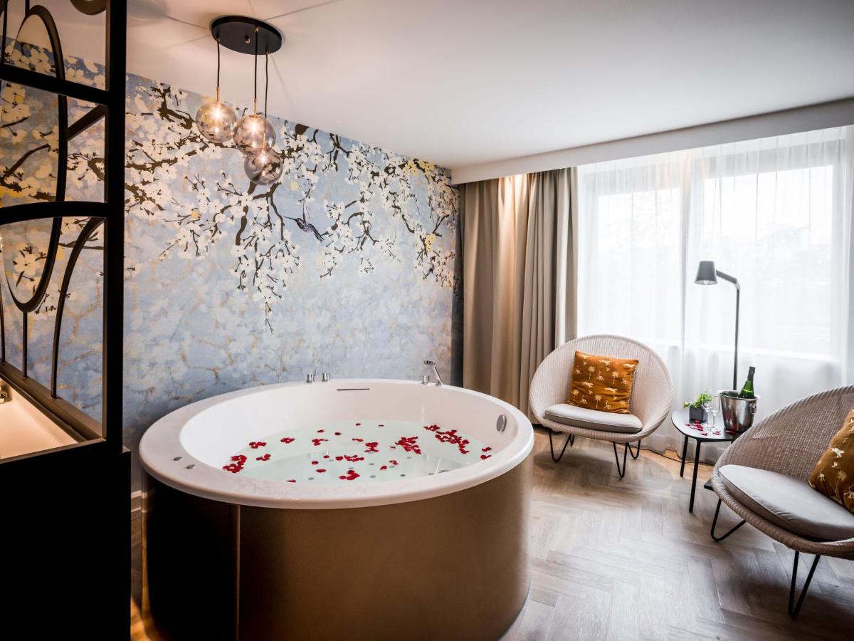 a bathroom with a tub with flowers on the wall at Hotel Van der Valk Maastricht in Maastricht