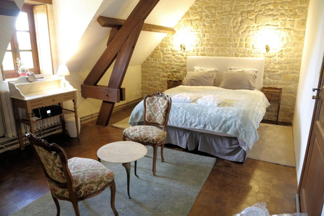 a bedroom with a bed and a table and chairs at Château du Bû in Anctoville