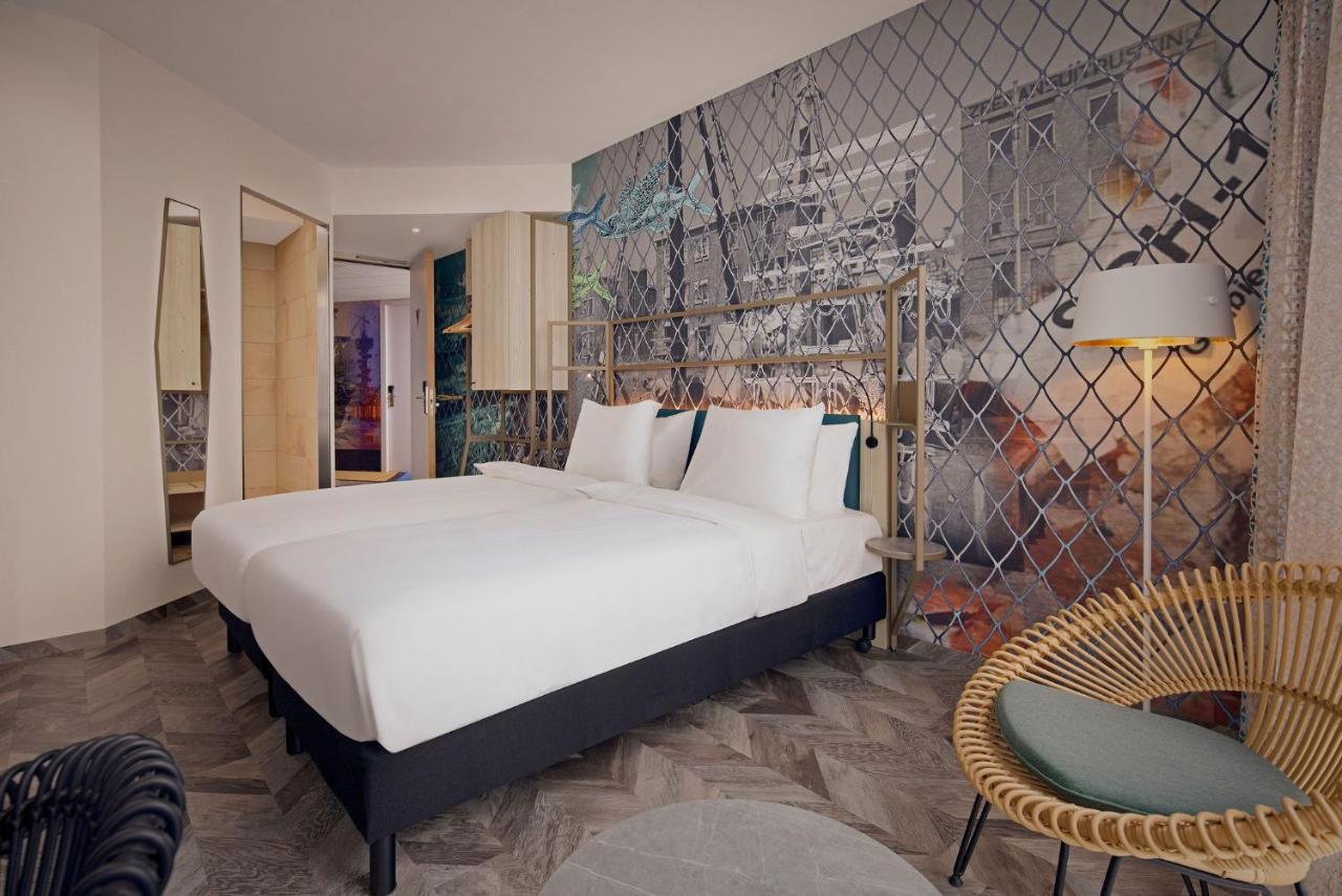 a bedroom with a large white bed and a chair at Inntel Hotels Den Haag Marina Beach in Scheveningen