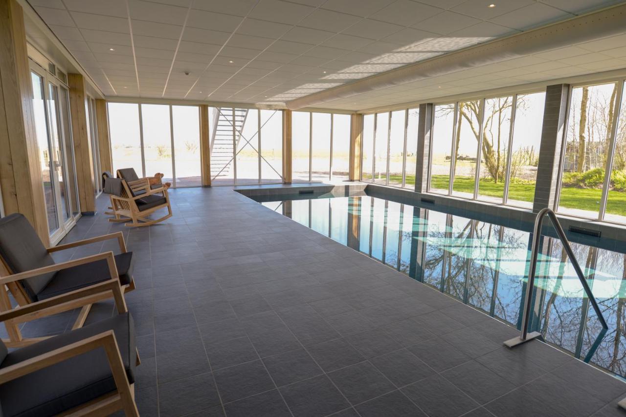 a swimming pool in a building with windows at Boutique Hotel Texel in De Cocksdorp