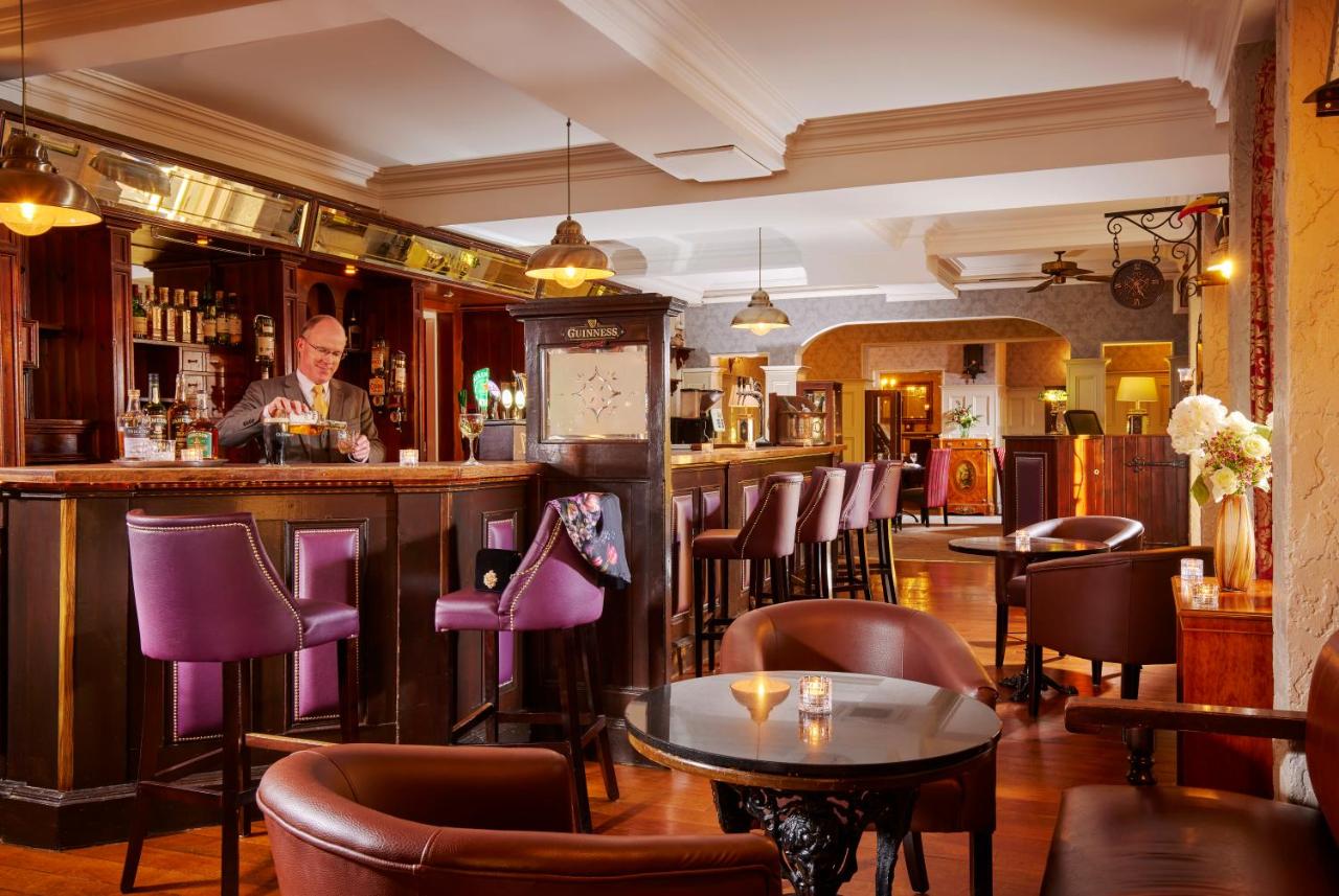 Warmly lit pub interior with a bartender serving drinks behind a wooden bar counter.