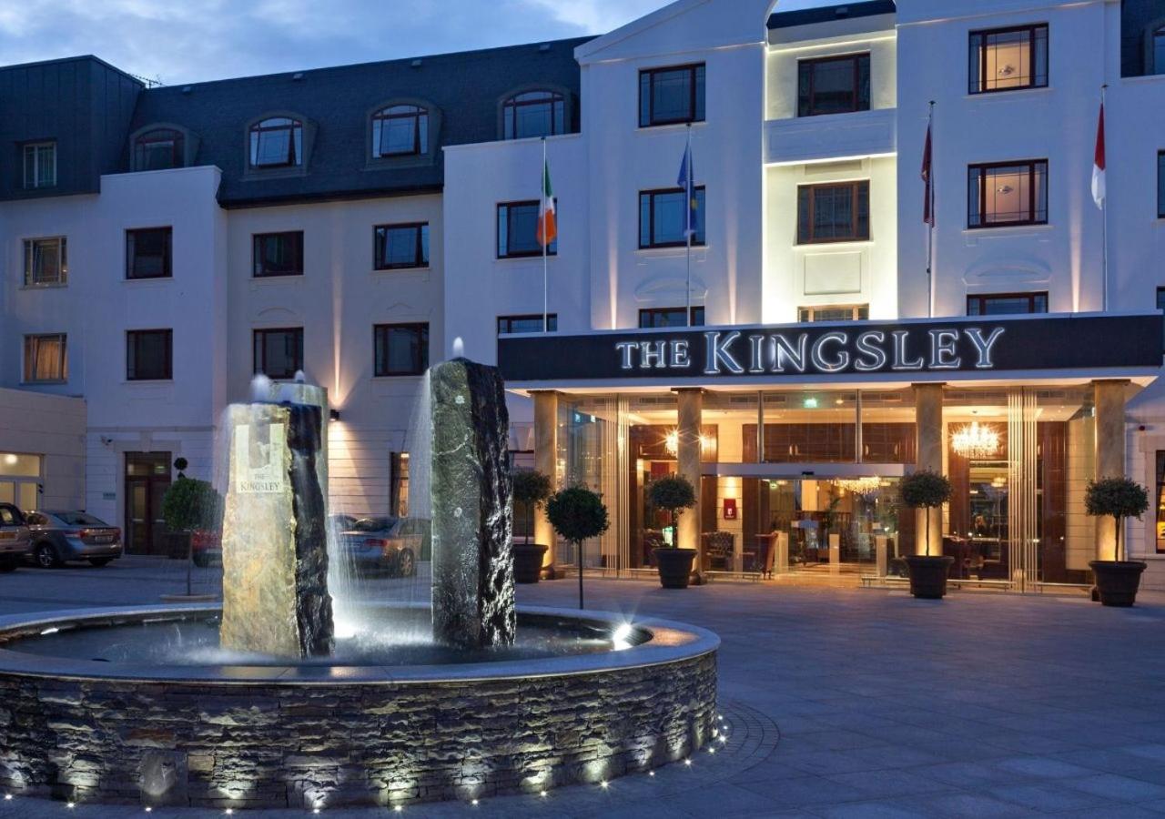 Hotel entrance with illuminated fountain and modern facade at dusk.