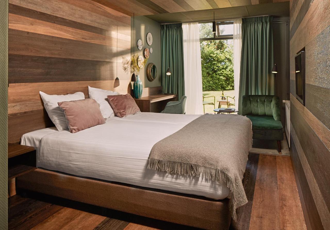 a bedroom with a large bed and a green chair at Prins Hendrik Texel in Oost