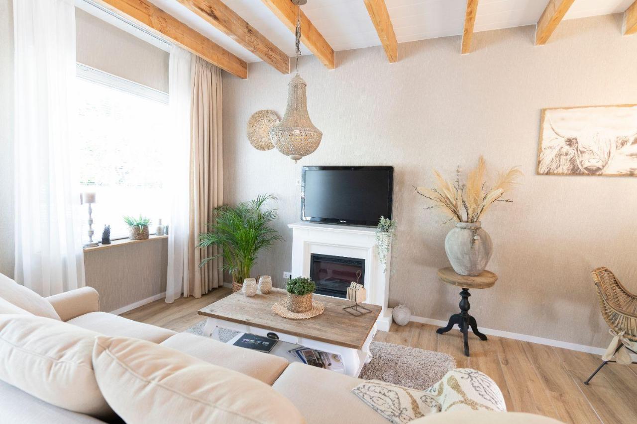 a living room with a white couch and a tv at B&B The Wellness Cottage in Dordrecht