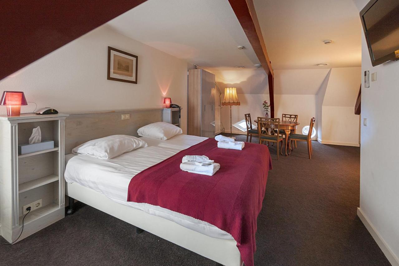 a bedroom with a large bed and a table at Hotel de Gaaper in Amersfoort