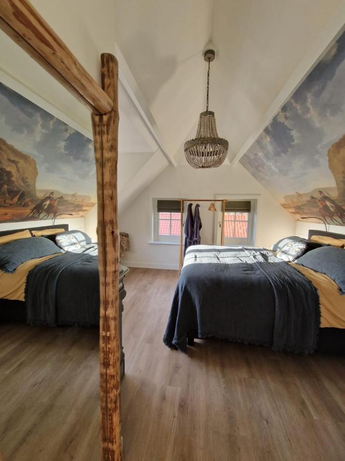 two beds in a room with paintings on the walls at Bed & Breakfast Hoeve Happiness - ontbijt inbegrepen - wellness aanwezig in Voorthuizen