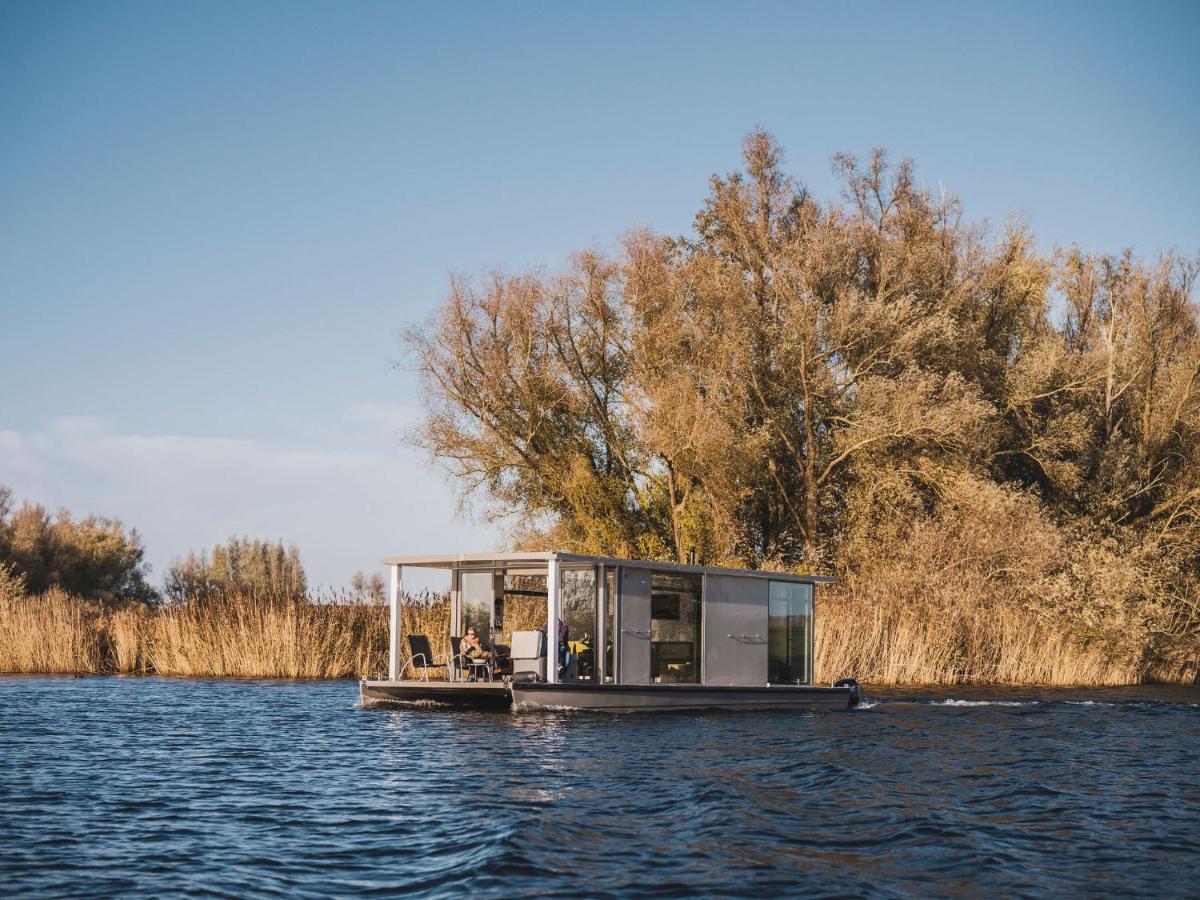 a small house on a boat in the water at AquaHome - NP de Biesbosch - Bijzonder overnachten op een houseboat! in Werkendam