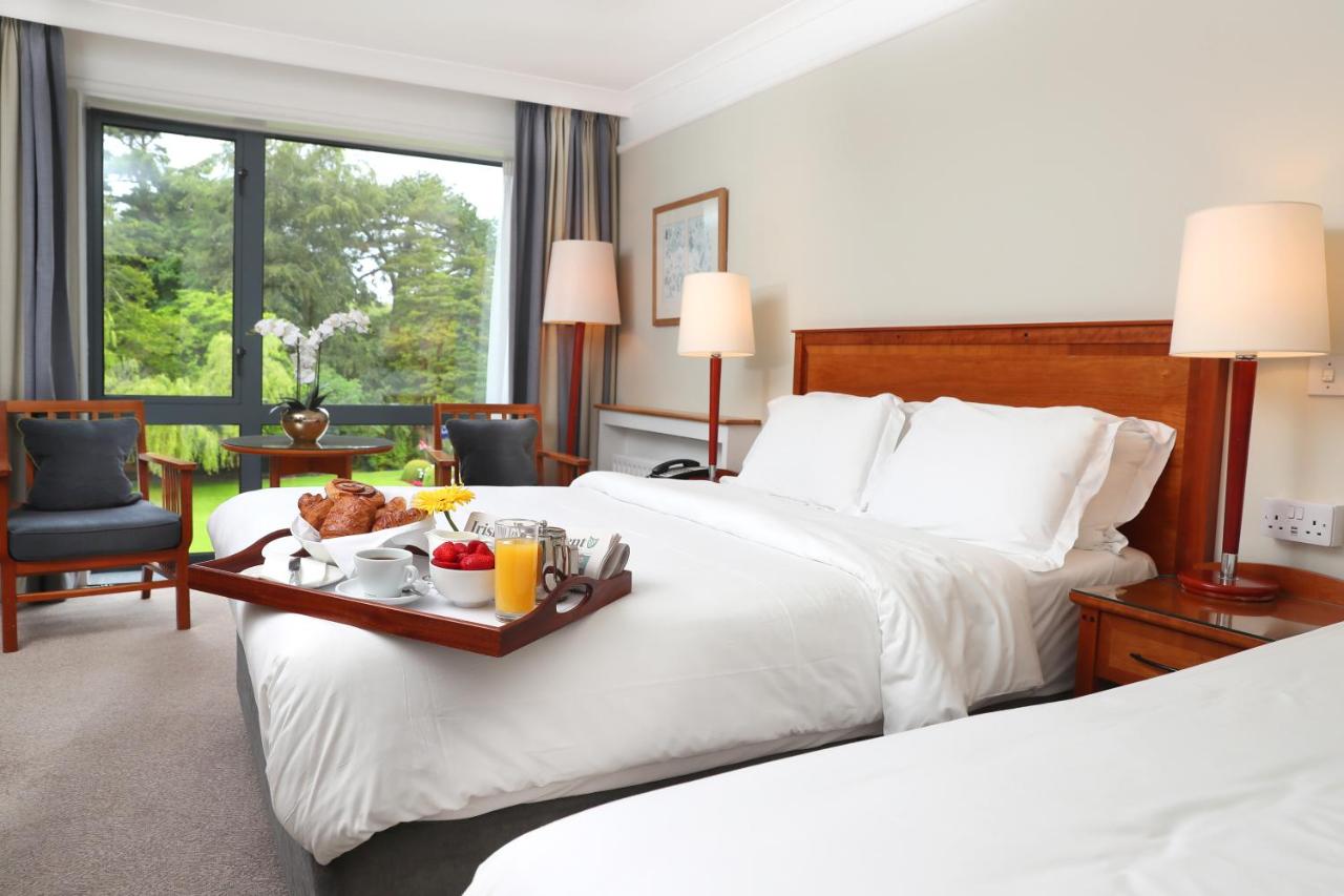Hotel room with two beds, a breakfast tray, and a view of greenery outside.