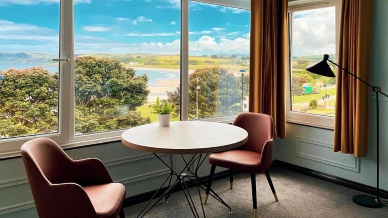 Room with a table, chairs, and a view of a coastal landscape.