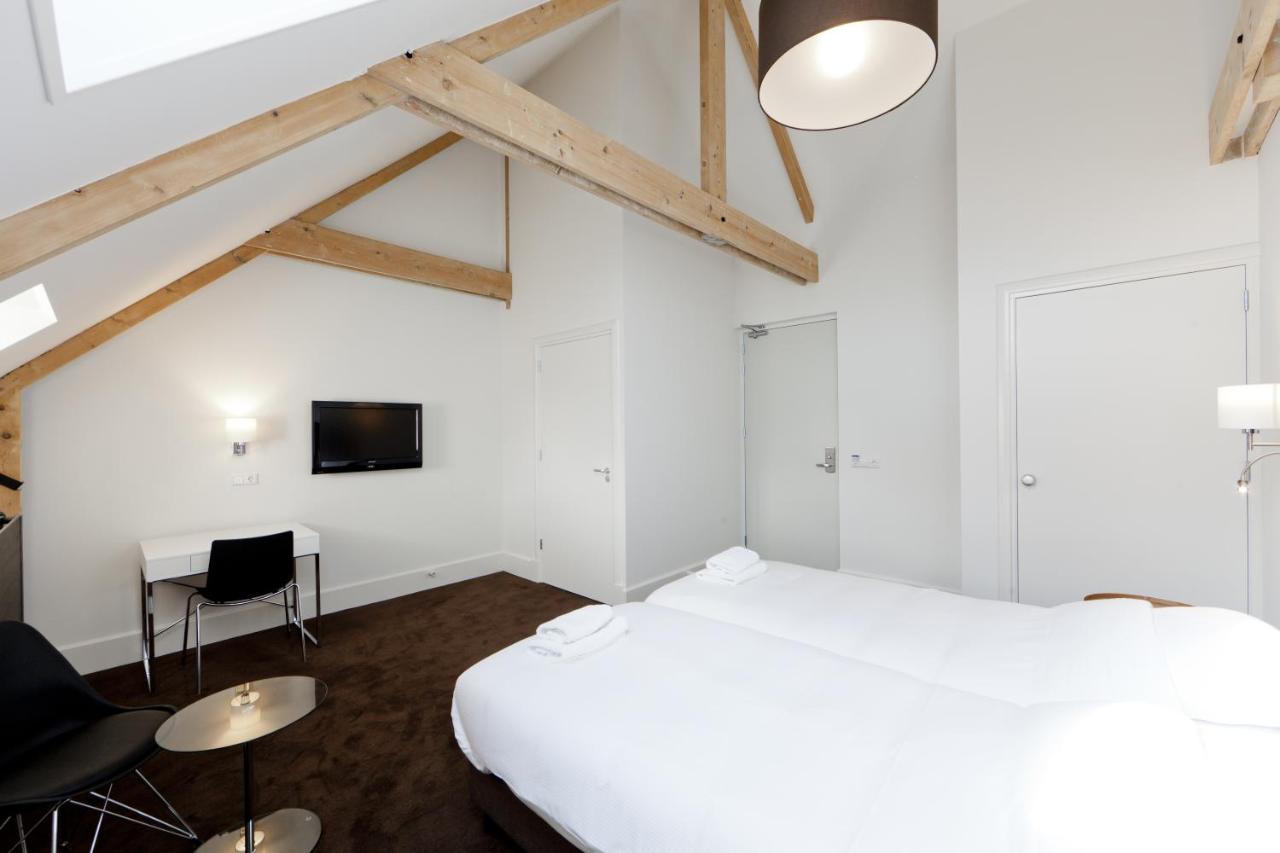 a bedroom with a bed and a desk and a tv at College Hotel Alkmaar in Alkmaar