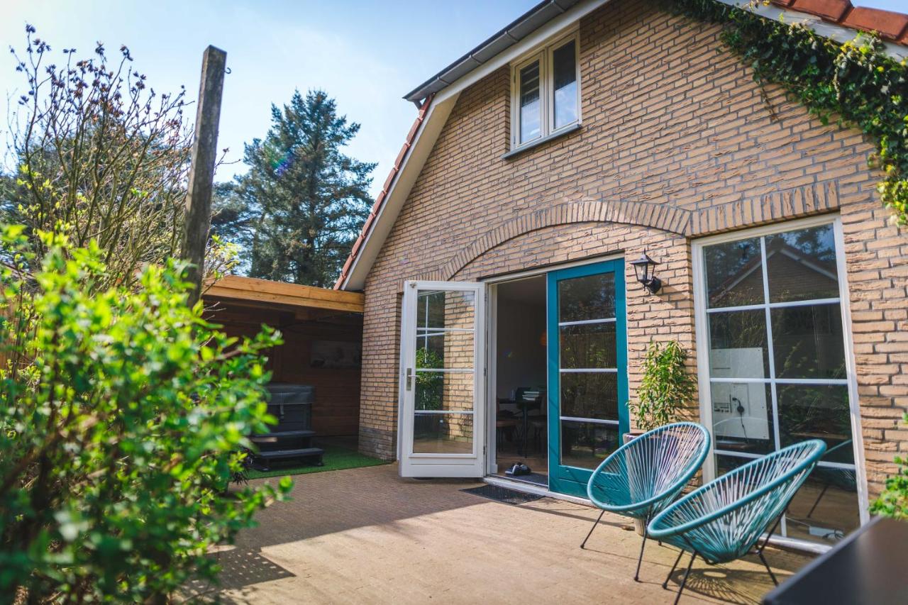 a house with two chairs and a door at Luxe Veluws Vakantiehuis met JACUZZI in Lunteren