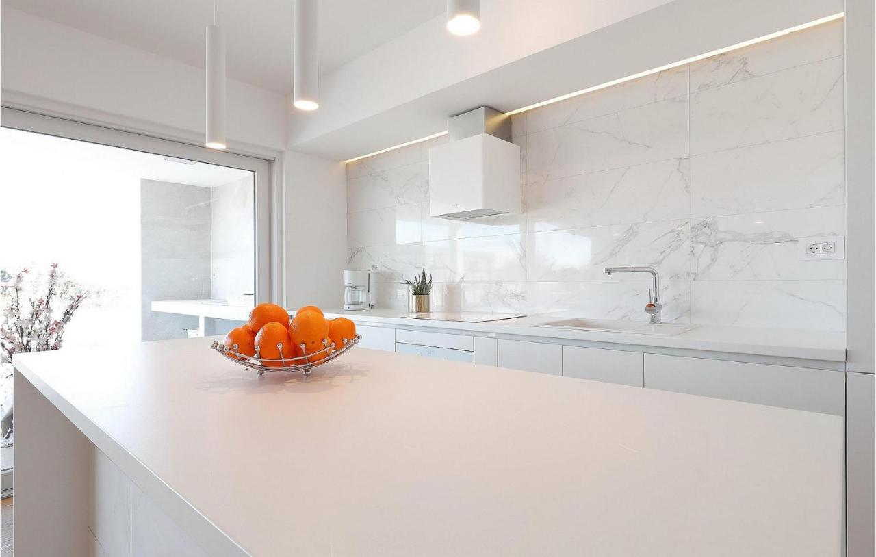 Minimalist white kitchen with a bowl of oranges on the counter