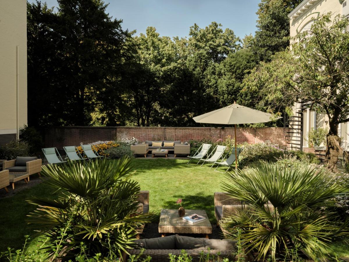 a garden with a table and an umbrella at Park Centraal Den Haag, part of Sircle Collection in The Hague
