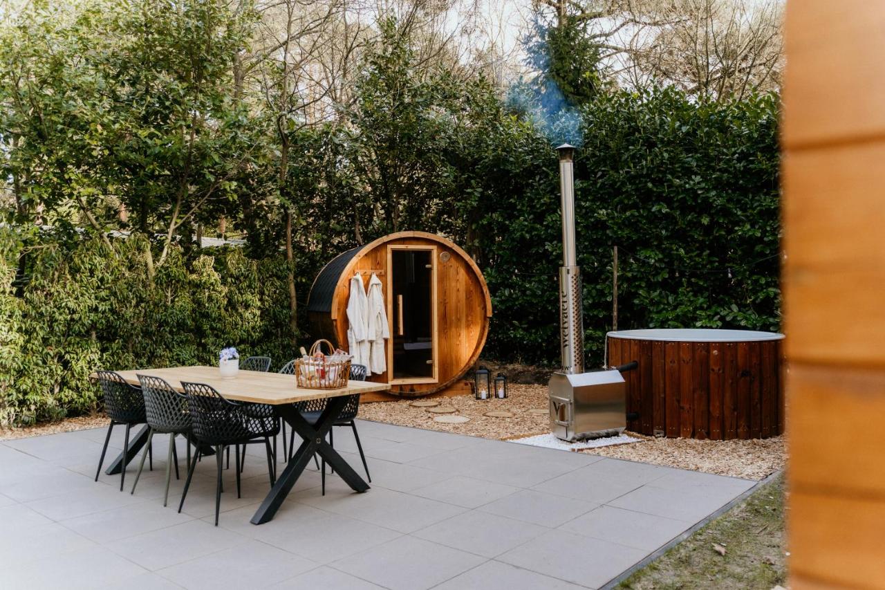 a patio with a table and chairs and a barrel at Romantisch Wellness Boshuisje met Sauna & Hottub in Meijel