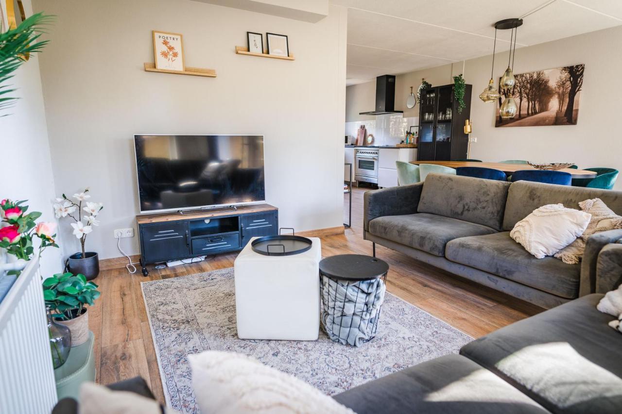 a living room with a couch and a tv at Wellnesshuis met jacuzzi en sauna in het bos in Lunteren