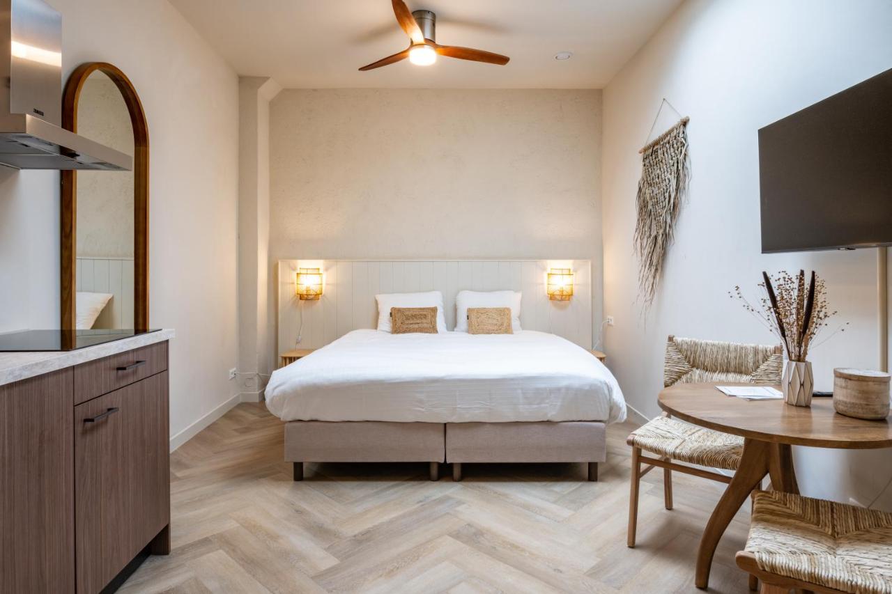 a bedroom with a bed and a table and a kitchen at Grapèlli Boutique Hotel in Alkmaar