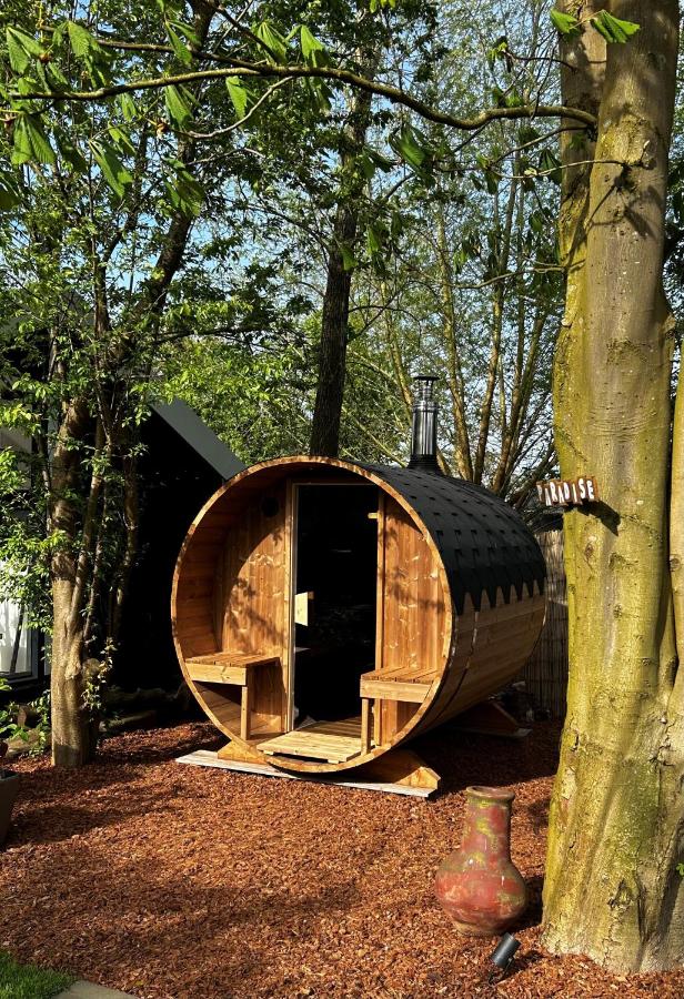 a wooden cabin in the woods with a tree at Casa aan de Plas, B&B met sauna en hottub of jacuzzi in Nieuwkoop