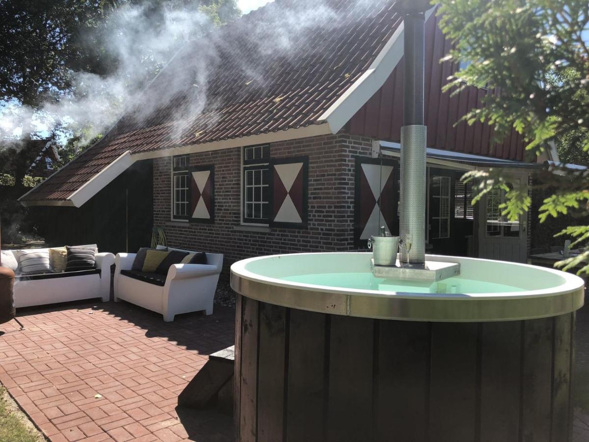 a hot tub in front of a house with smoke at De Brittenburg 4-persoons, finse sauna, hottub, sunshower, grote zonnige omheinde tuin, wifi en huisdier vriendelijk in Lievelde