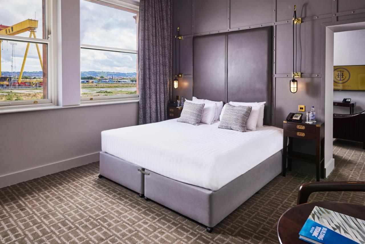 Hotel room with large bed, modern decor, and view of an industrial crane outside.