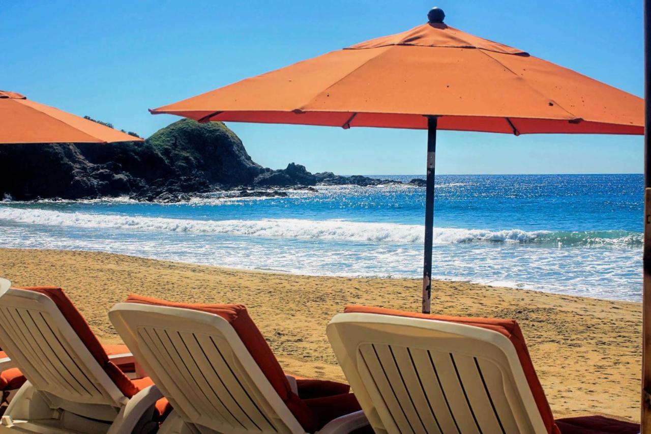 orange sun lounges and umbrella in front of the beach