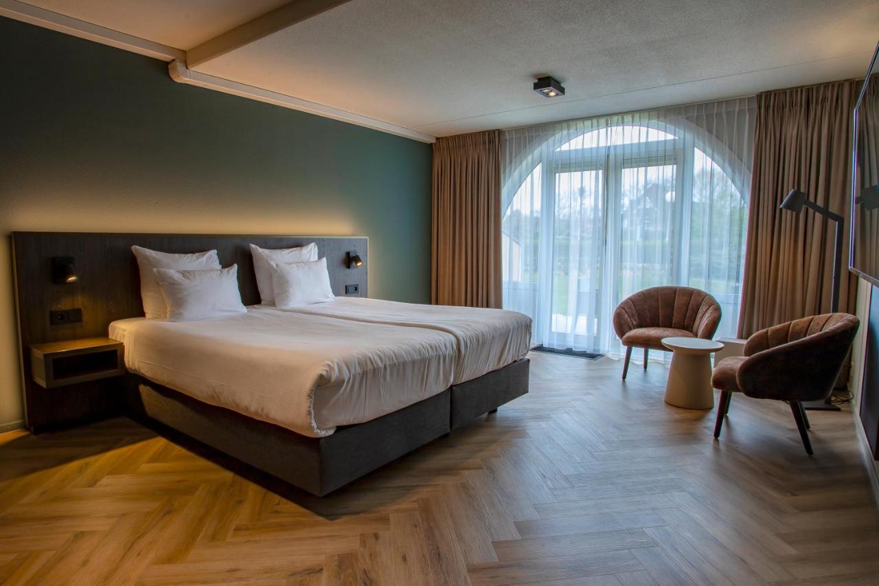 a hotel room with a bed and a large window at Hotel Greenside Texel in De Koog