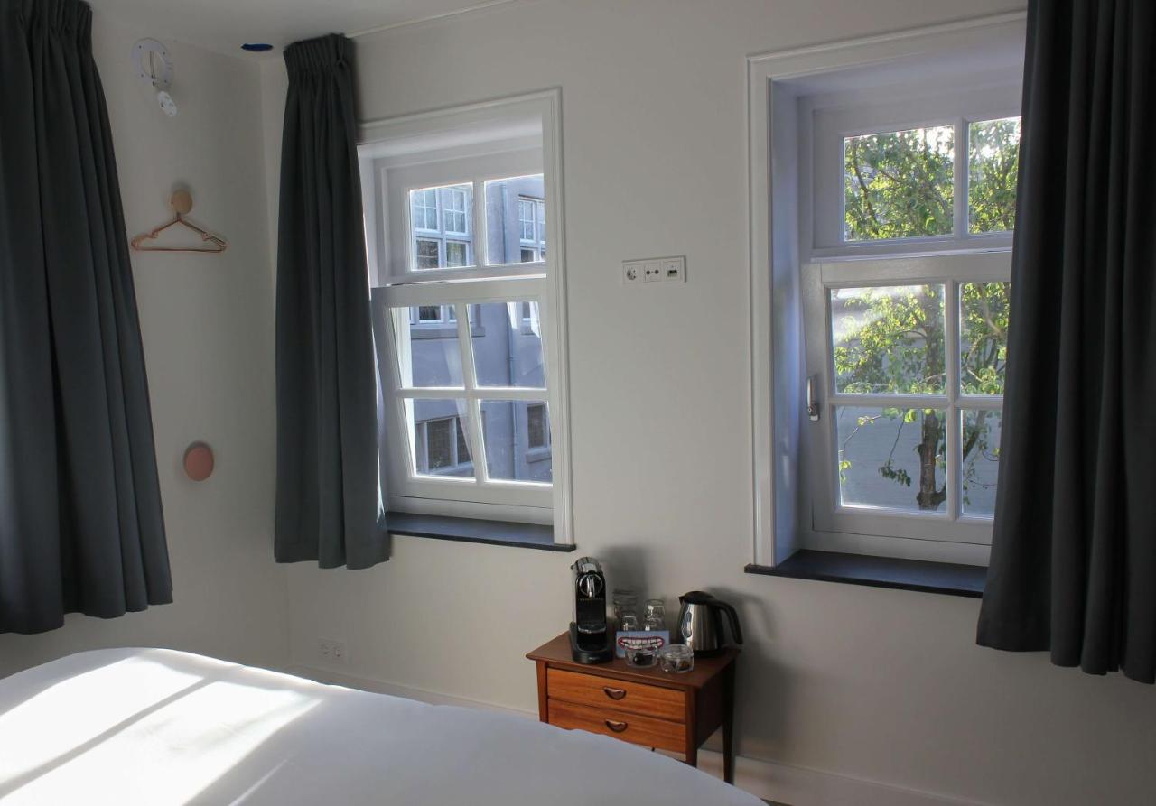 a bedroom with two windows and a bed and a wooden table at Boutique Hotel Nieuw Uilenburg in Den Bosch