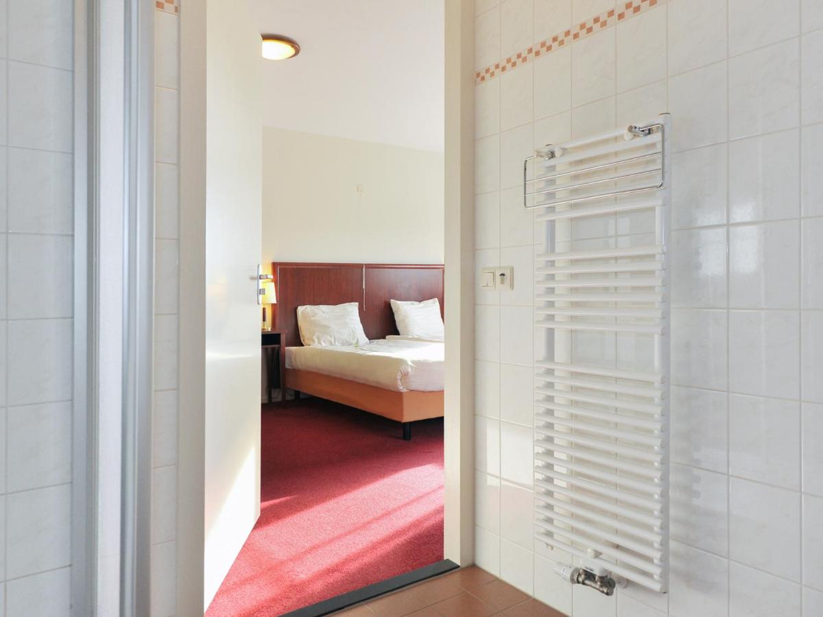 a bathroom with a bedroom with a bed and a mirror at de Brabantse Biesbosch in Werkendam