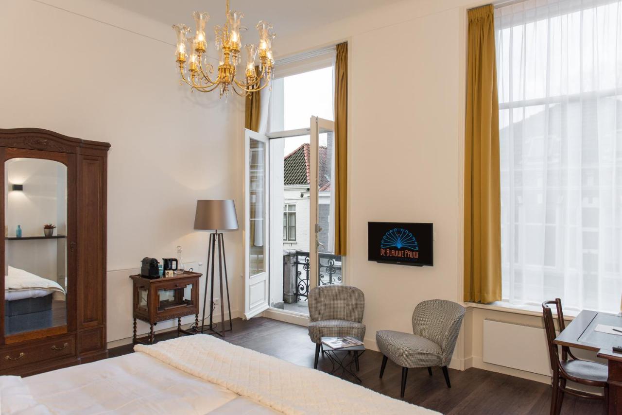 a bedroom with a bed and a chandelier at Boutique Hotel De Blauwe Pauw in Den Bosch