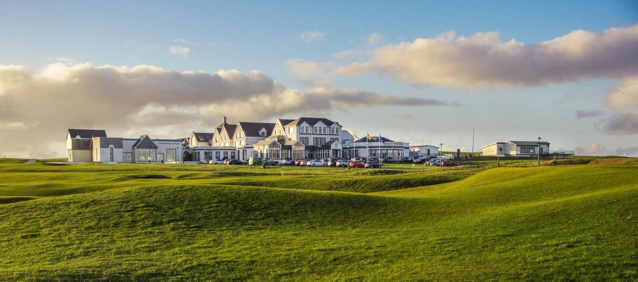 Coastal building complex with green lawns and cloudy sky backdrop.
