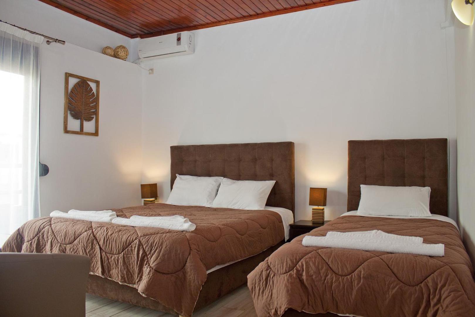 Gaišs numurs ar divām gultām, brūniem galvgaļiem un koka griestu apdari.