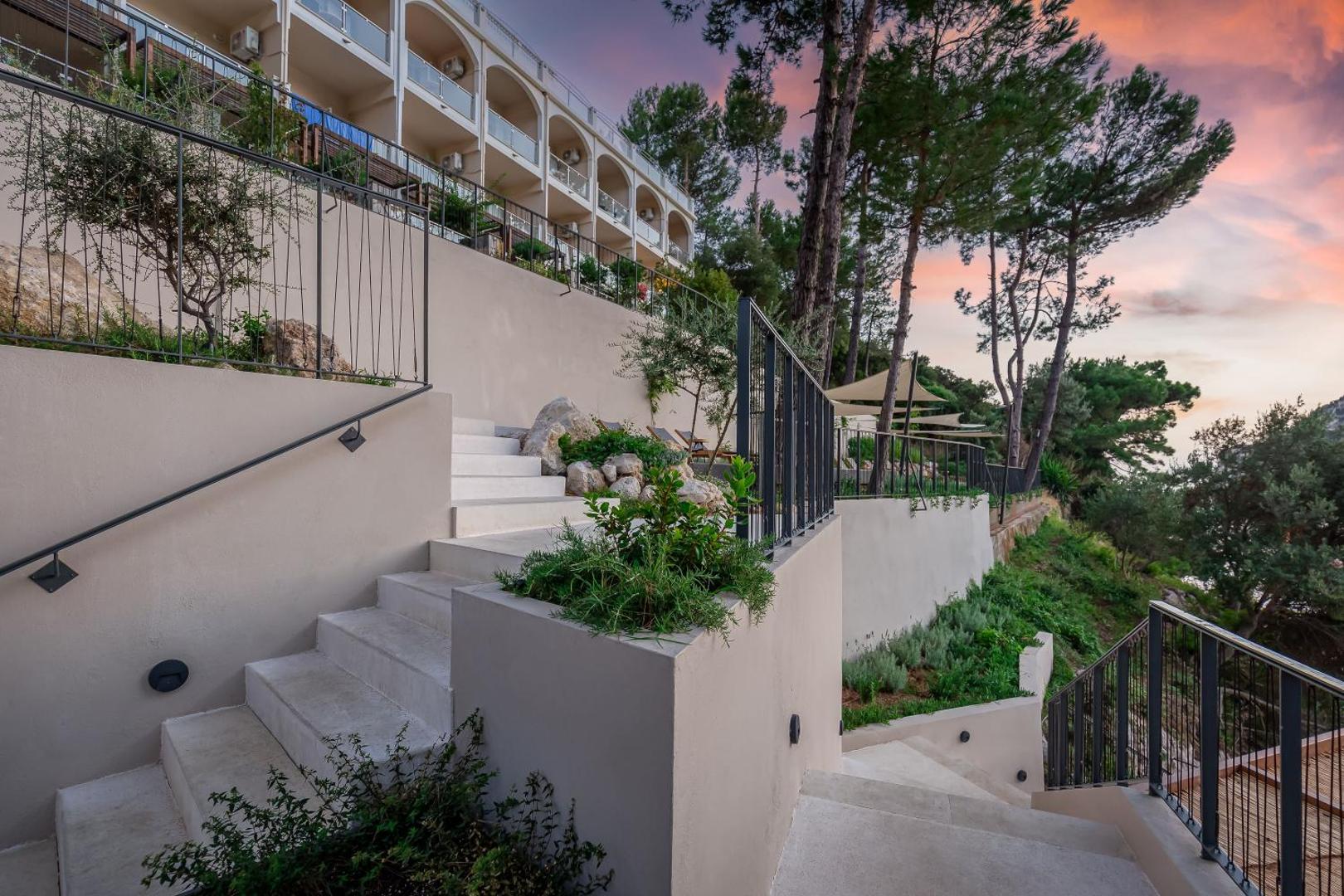 Gaišas āra kāpnes un terases ar margām uz saulrieta debesu fona.