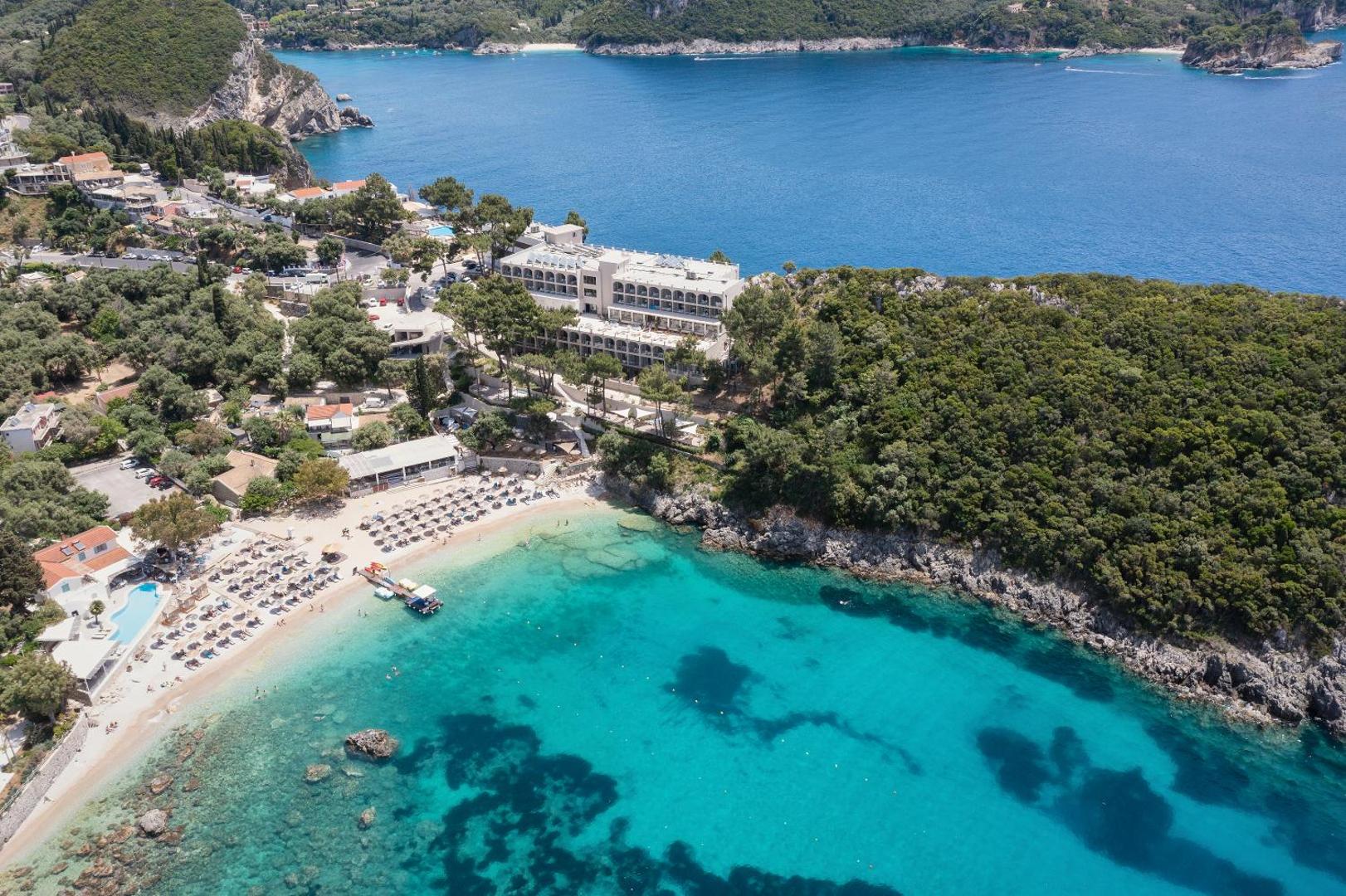 Skats no putna lidojuma uz viesnīcu, zaļo pussalu un tirkīzzilu līci ar pludmali.