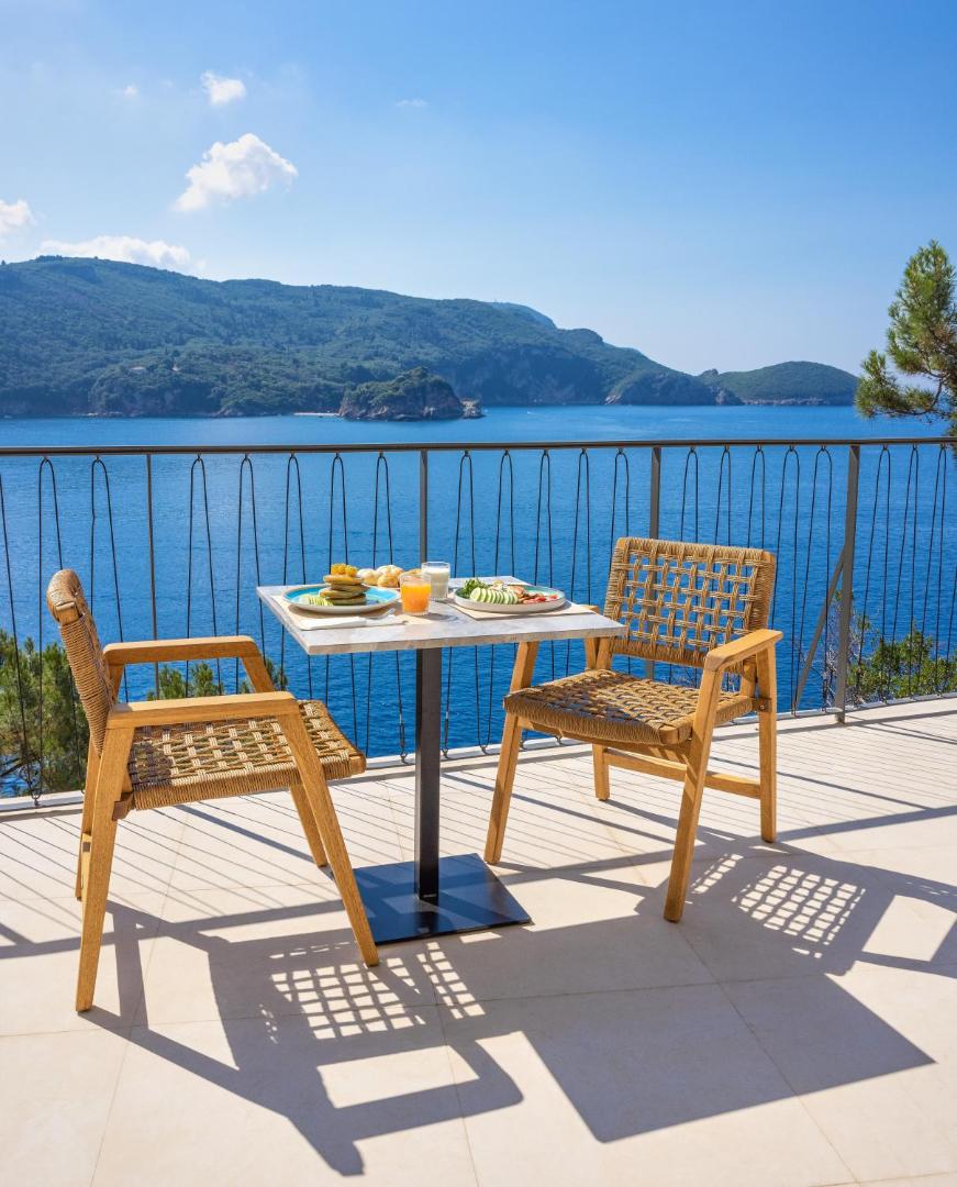 Brokastis uz terases ar skatu uz zilo jūru un zaļajiem kalniem.