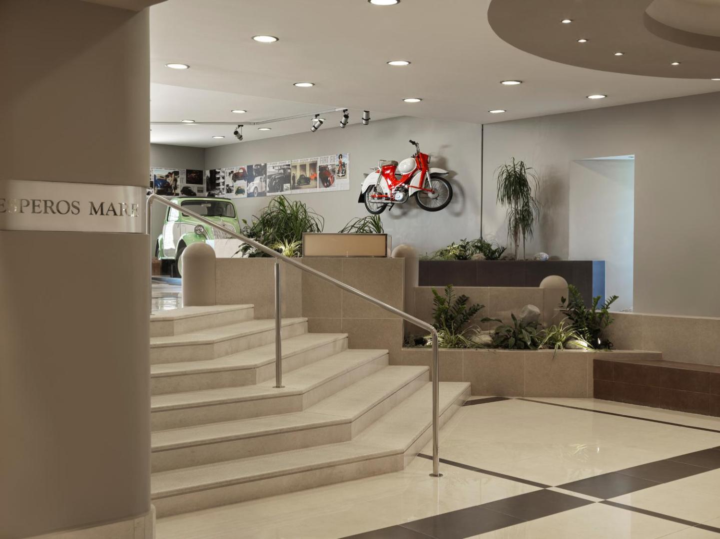 Viesnīcas vestibils ar marmora kāpnēm un unikālu retro motociklu un auto dekoru.
