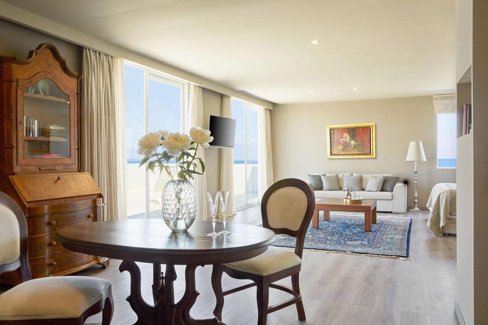 Elegants viesnīcas numurs ar klasiskām mēbelēm, atpūtas zonu un skatu uz jūru.