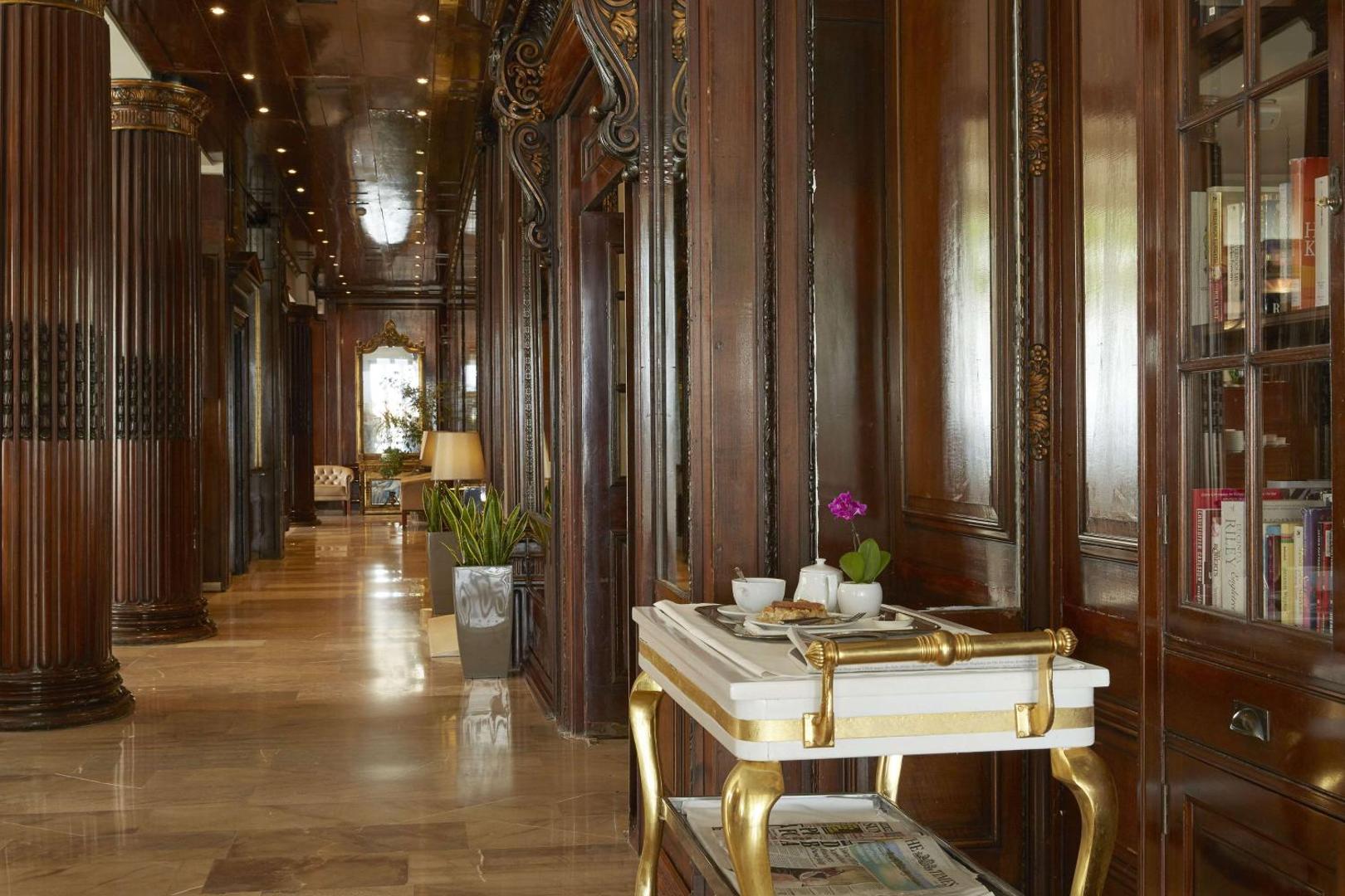 Gaišs gaitenis ar koka sienām, grāmatu skapi un servēšanas ratiņiem priekšplānā.