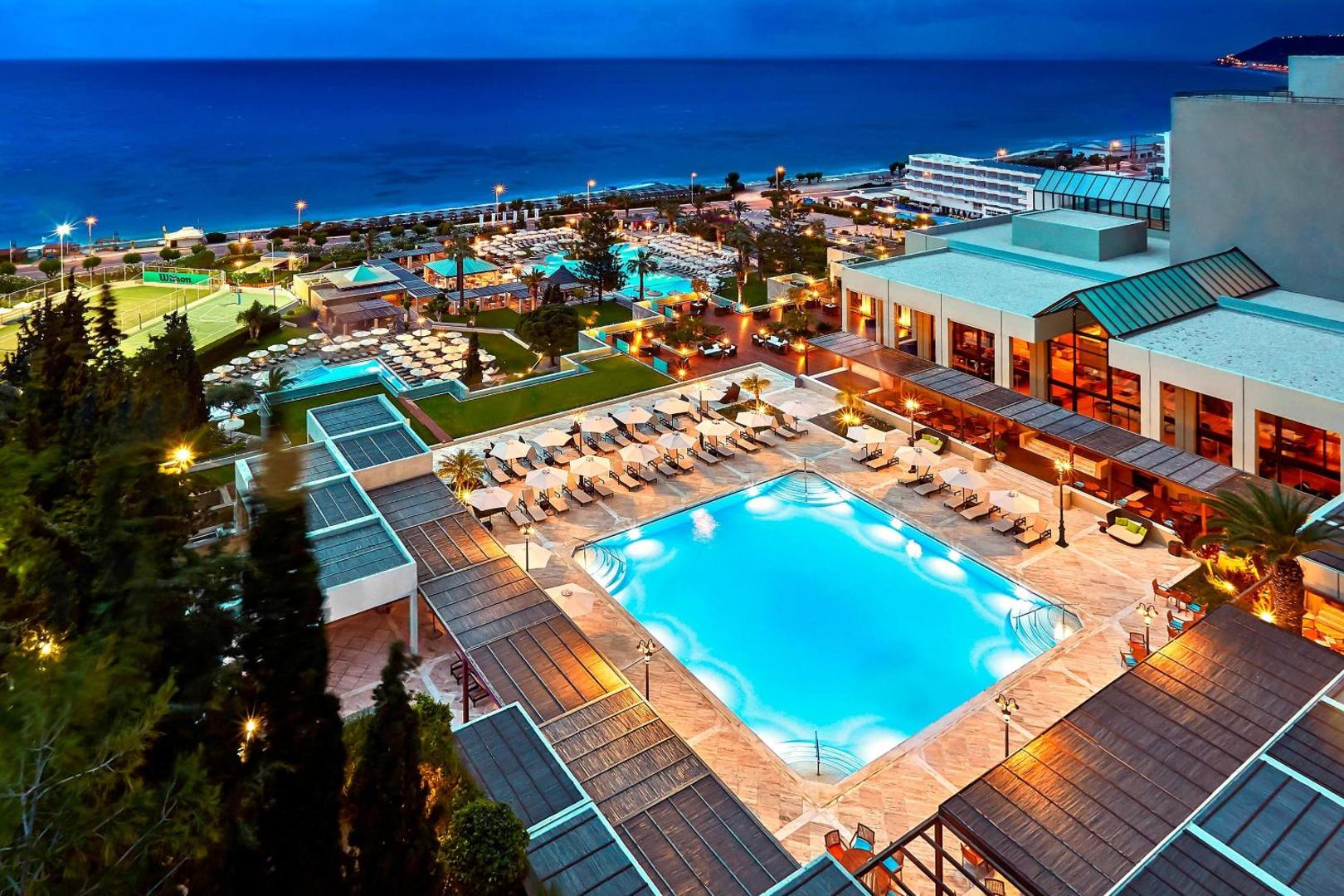 Sheraton Rhodes Resort āra baseini un teritorija izgaismota vakarā pie jūras.