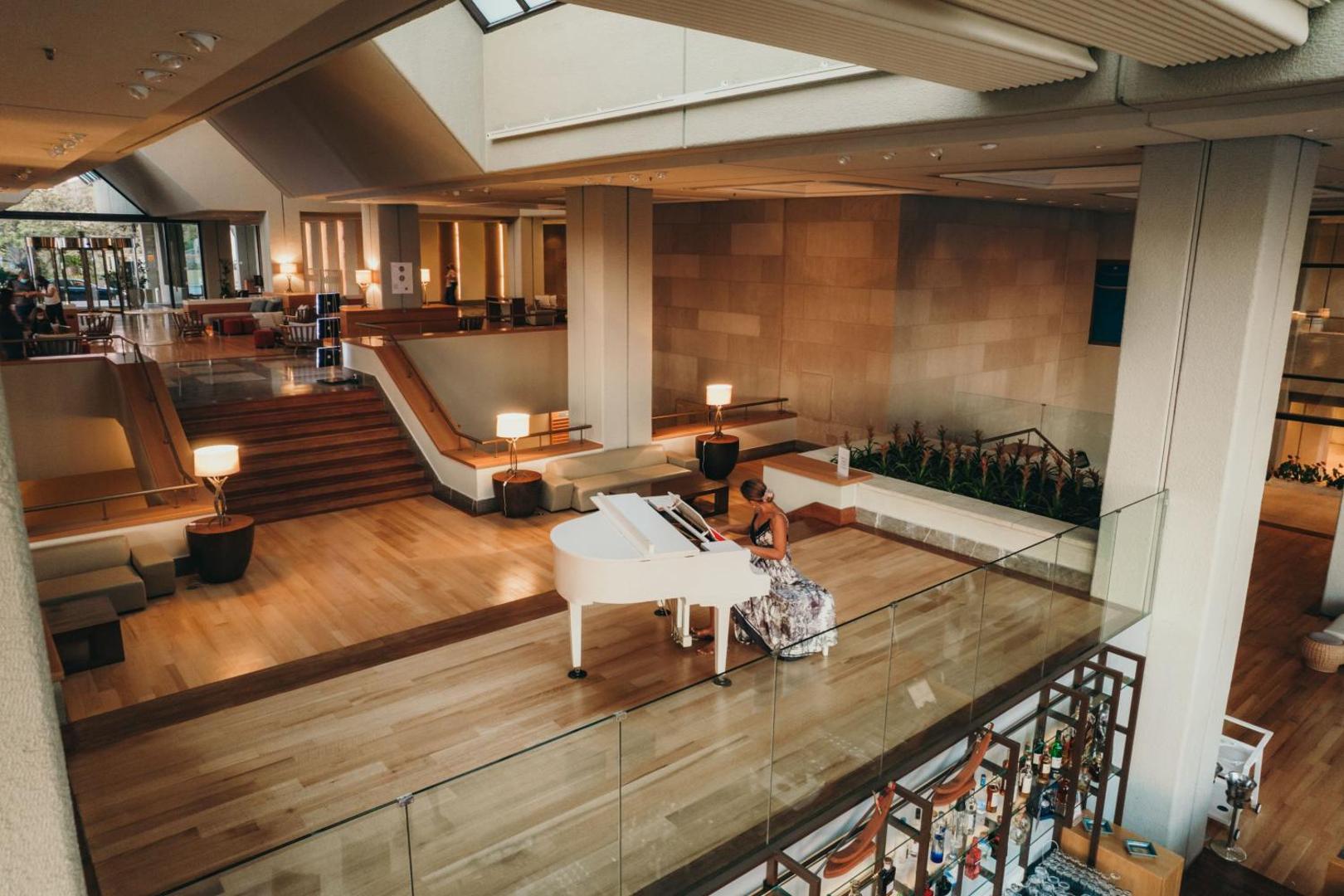 Sieviete spēlē baltas klavieres Sheraton Rhodes Resort viesnīcas atpūtas zonā.