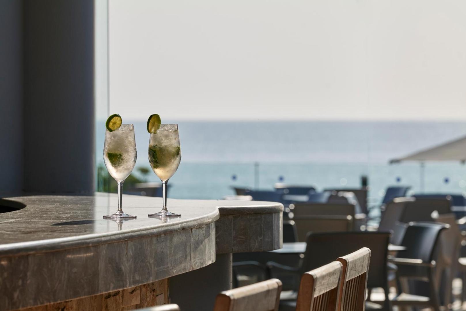 Divi atvēsinoši kokteiļi ar laimu uz marmora bāra letes ar skatu uz jūru.