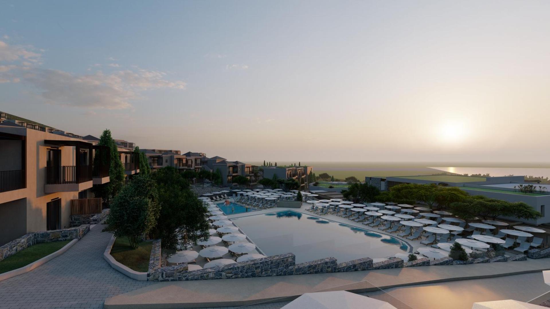 Elios Hill kūrorta panorāmas skats ar peldbaseiniem un saulrietu piekrastē.