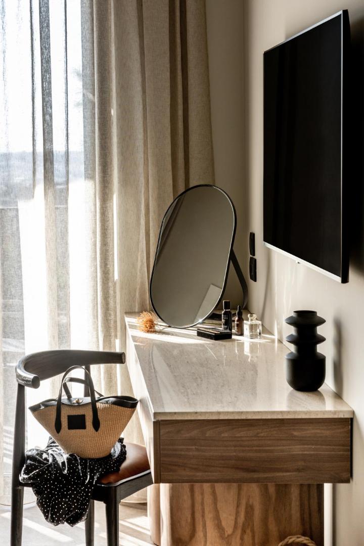 Elios Hill numura elegants tualetes galdiņš ar spoguli un dizaina elementiem pie loga.