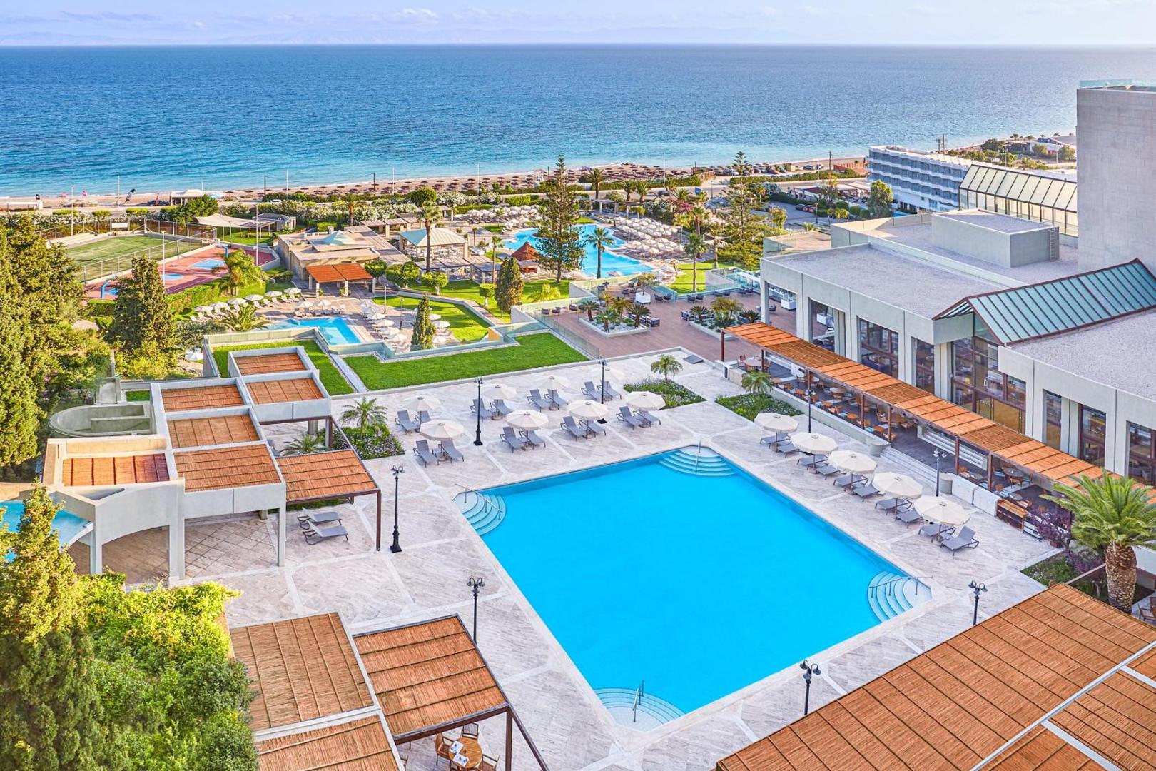 Panorāmas skats uz Sheraton Rhodes Resort baseiniem, dārzu un pludmali dienā.